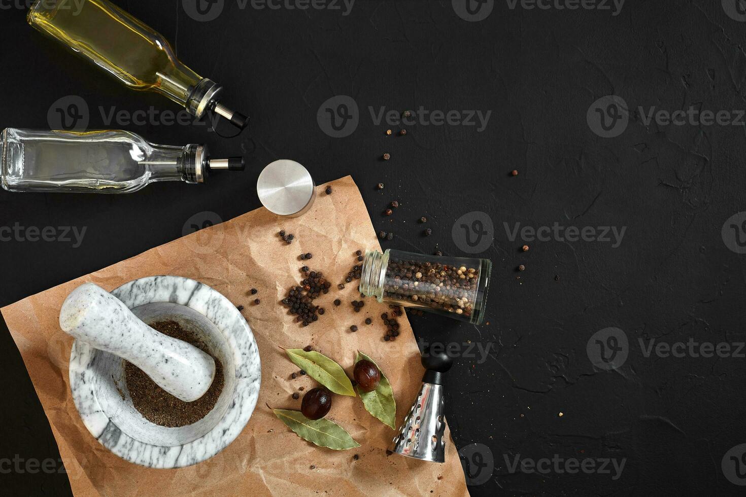 White mortar and pestle with dried peppers in flat lay on black background photo