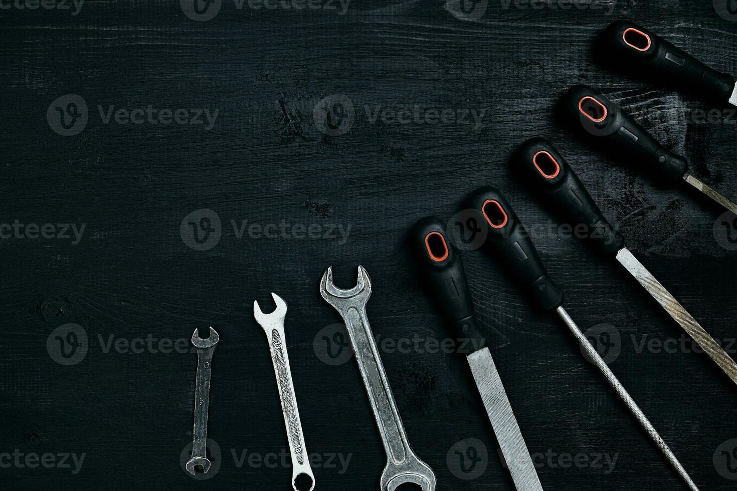 Series of many sharp steel blades and wrenches on black wooden background photo