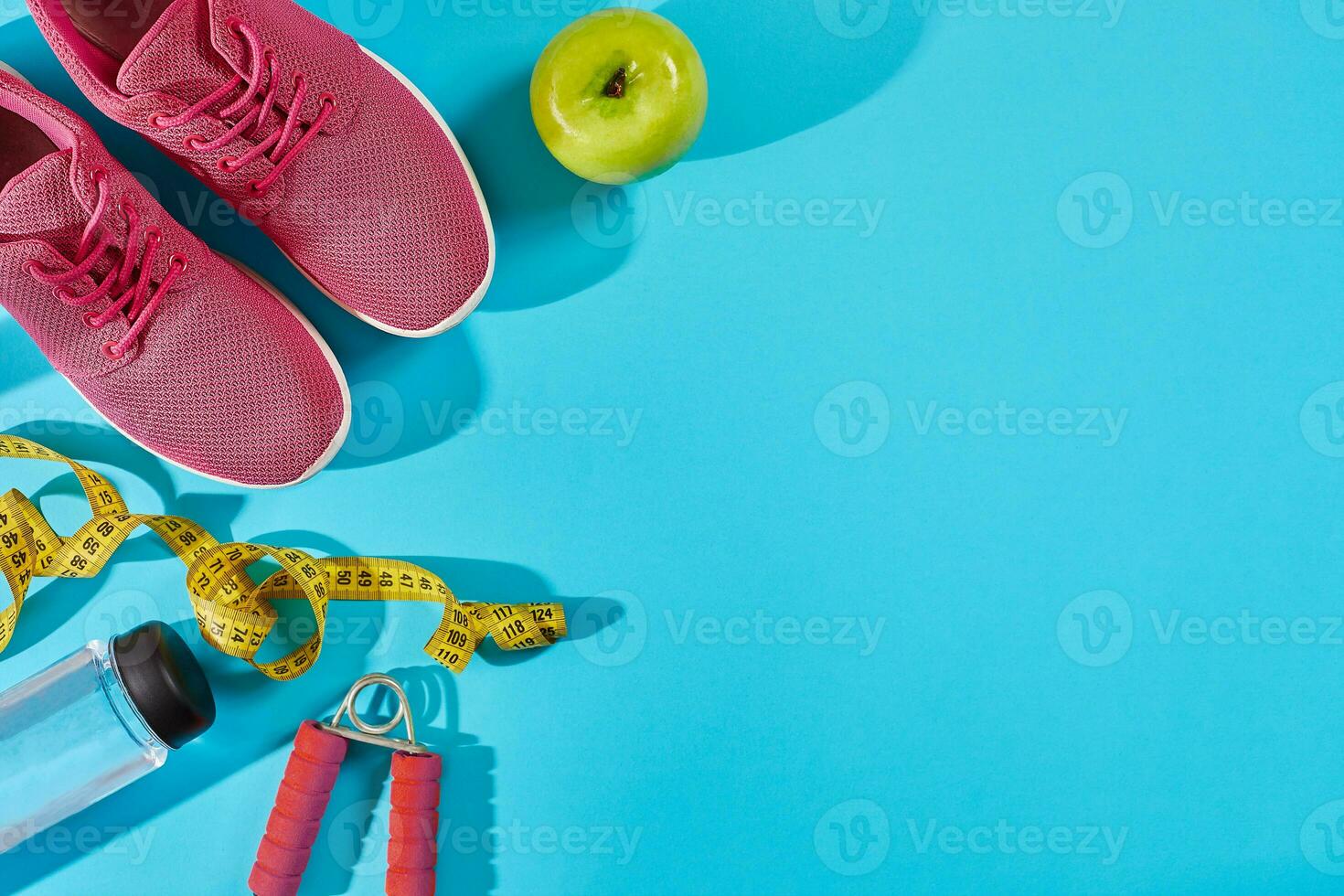 Sneakers with measuring tape on cyan blue background. Centimeter in yellow color near pink trainers, close up. photo