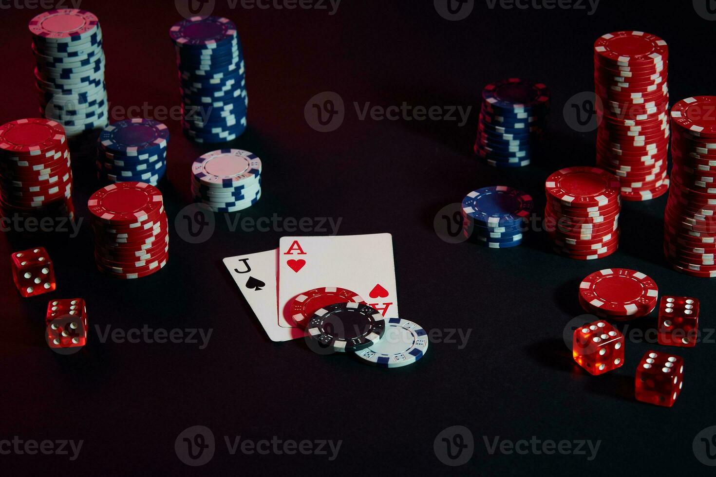 Casino chips and cards on black table surface. Gambling, fortune, game and entertainment concept - close up photo