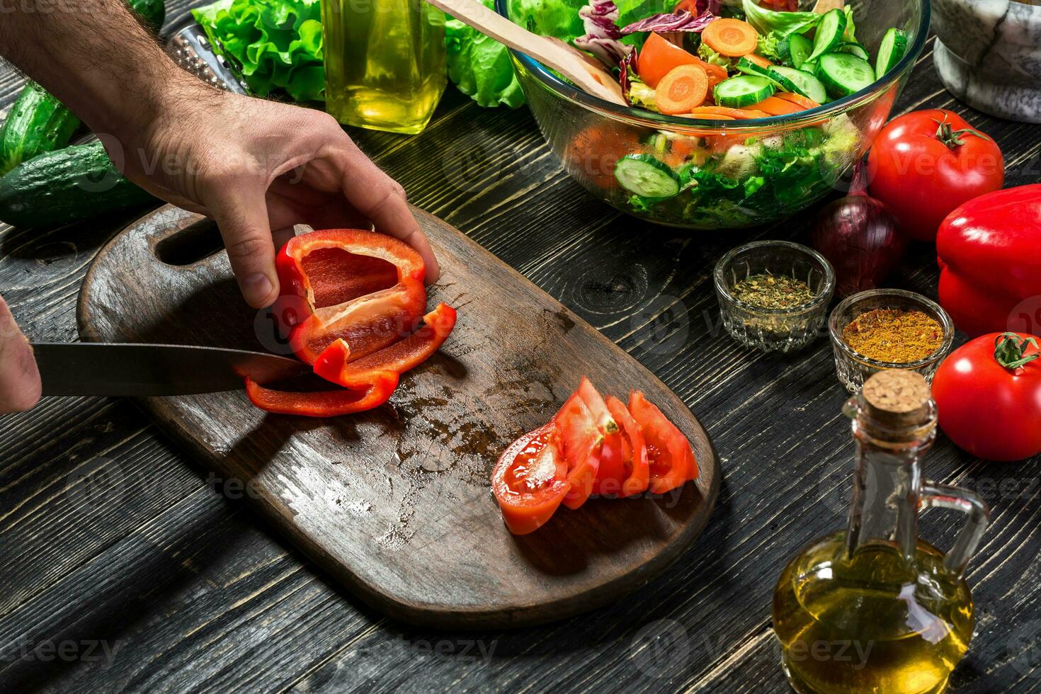 Man's hands cutting red paprika with knife. Cook cut red paprika. Man loves cooking fresh salad for dinner. Paprika cut by cook's hand. photo
