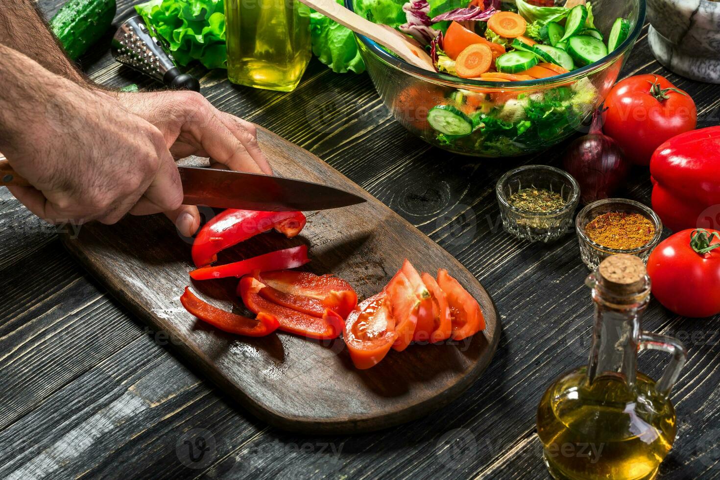 Man's hands cutting red paprika with knife. Cook cut red paprika. Man loves cooking fresh salad for dinner. Paprika cut by cook's hand. photo