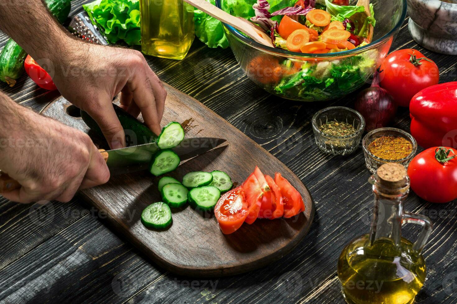 el hombre es corte el Pepino en el cocina en su casa a preparar ensalada a lo largo con comiendo cena. foto