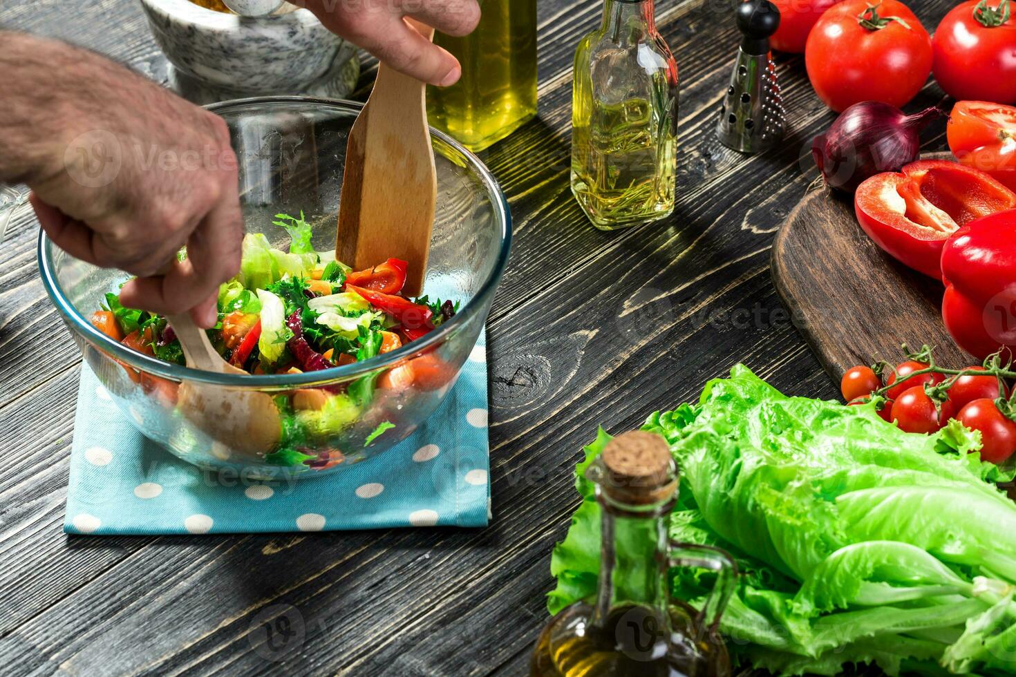 Man preparing salad with fresh vegetables on a wooden table. Cooking tasty and healthy food. Close-up photo