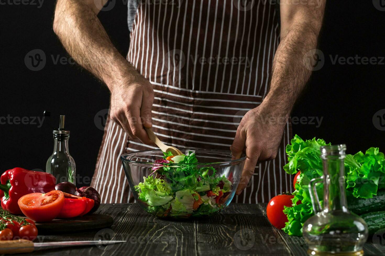Man preparing salad with fresh vegetables on a wooden table. Cooking tasty and healthy food photo