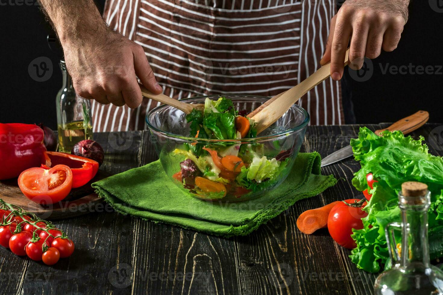 Man preparing salad with fresh vegetables on a wooden table. Cooking tasty and healthy food photo