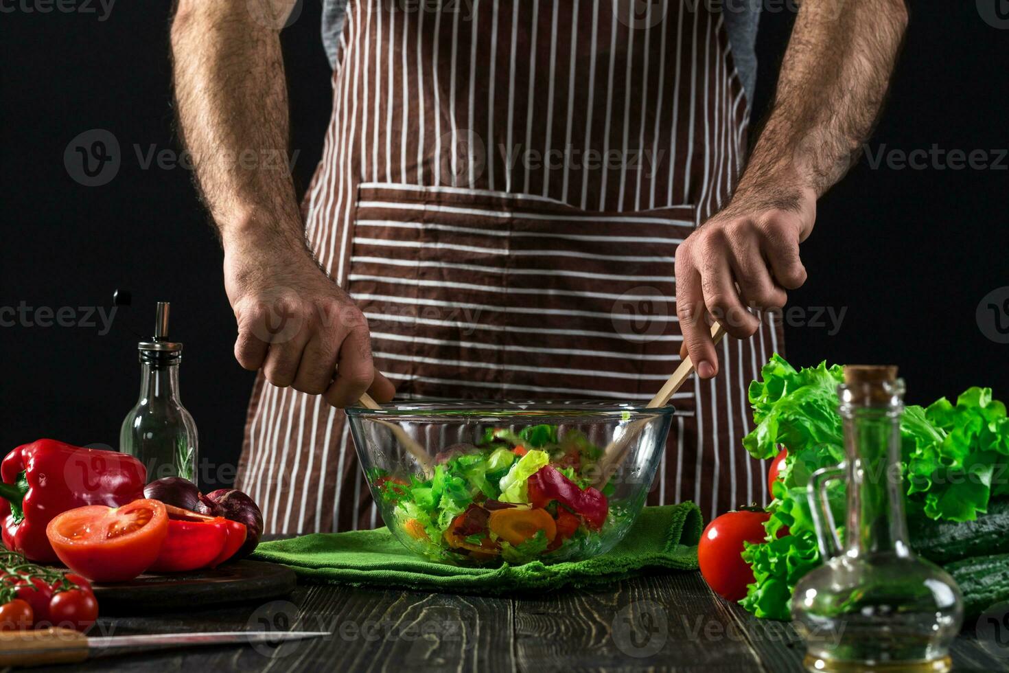 Man preparing salad with fresh vegetables on a wooden table. Cooking tasty and healthy food photo