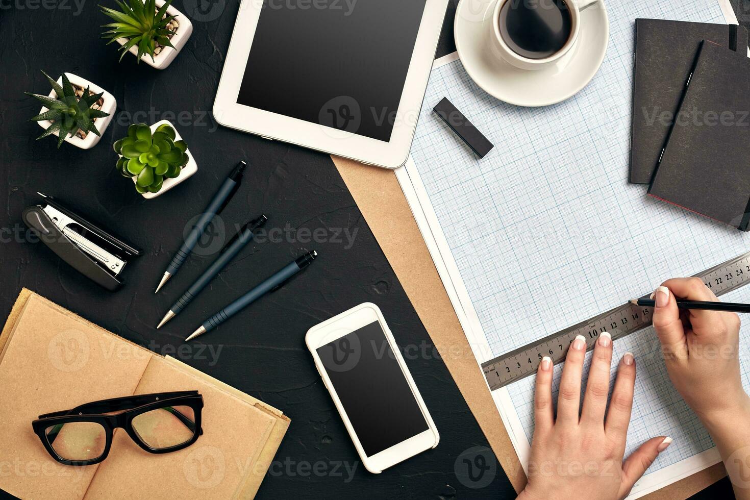 Office desk background hand with pen writing construction project ideas concept. With tablet, drawing equipment and a cup of coffee. View from above photo