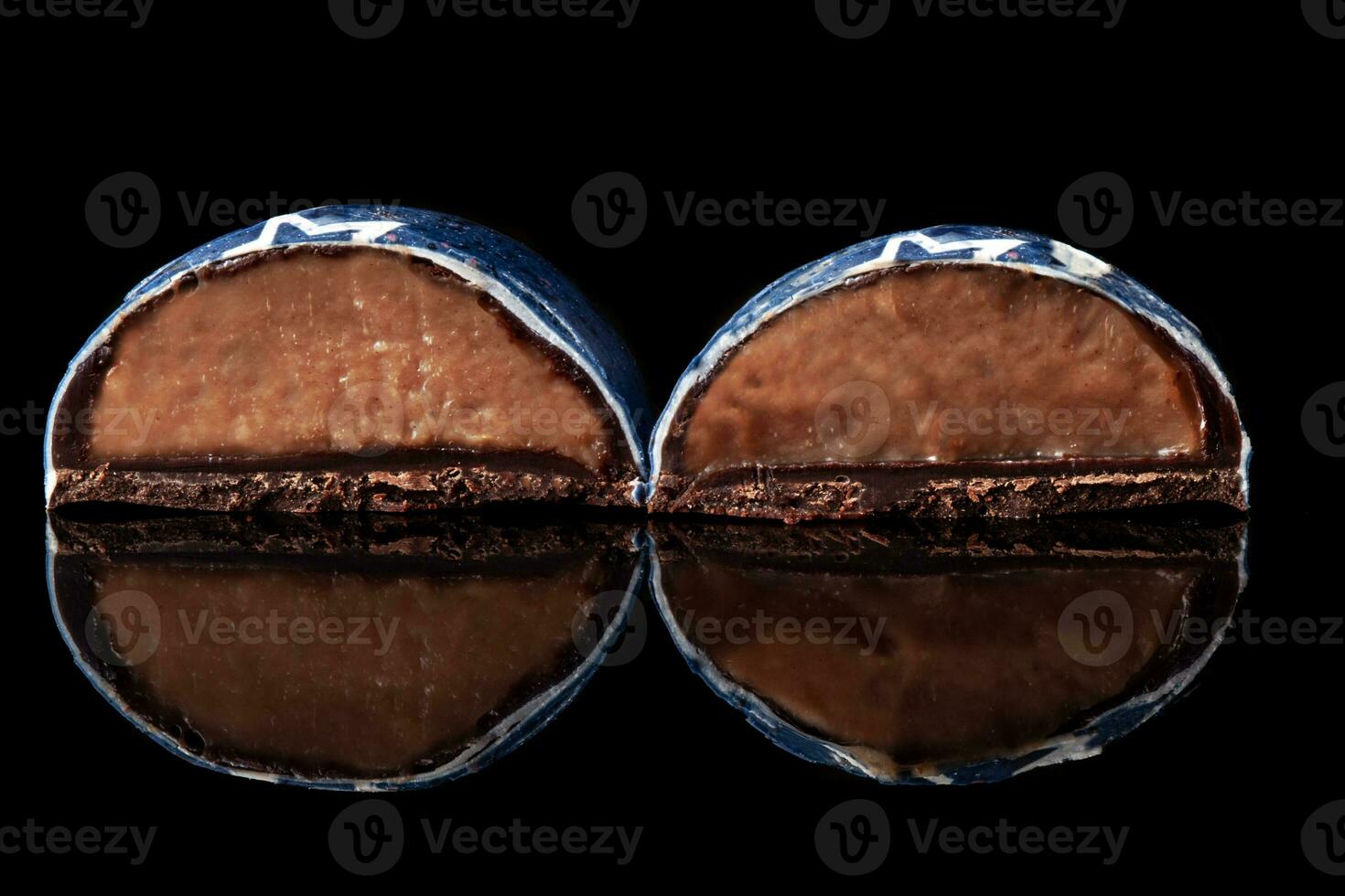 Cut luxury handmade candy with chocolate and yellow confiture filling on black background. photo