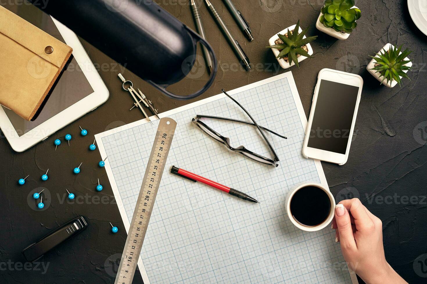 Office desk background hand with pen writing construction project ideas concept. With tablet, drawing equipment and a cup of coffee. View from above photo