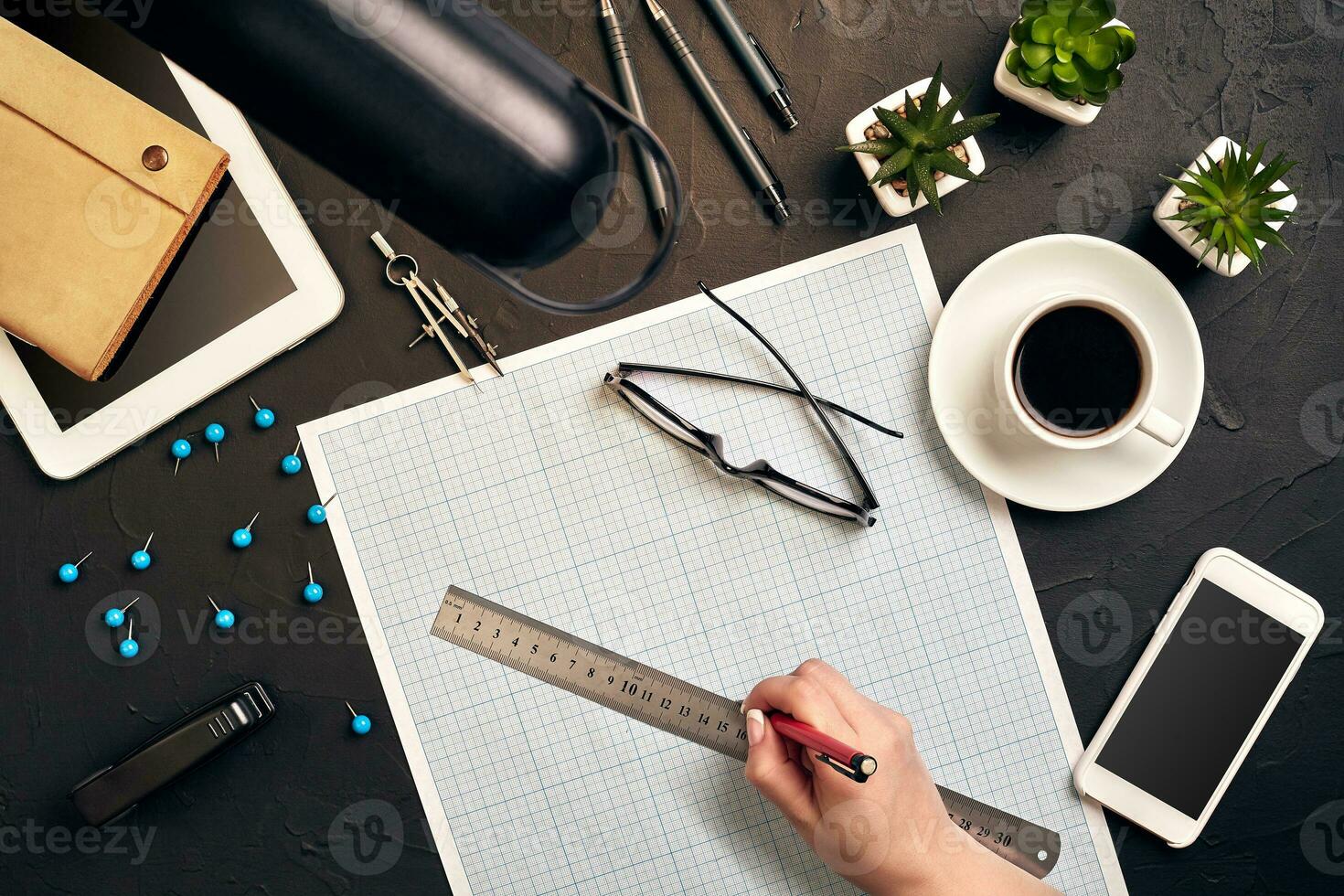 Office desk background hand with pen writing construction project ideas concept. With tablet, drawing equipment and a cup of coffee. View from above photo