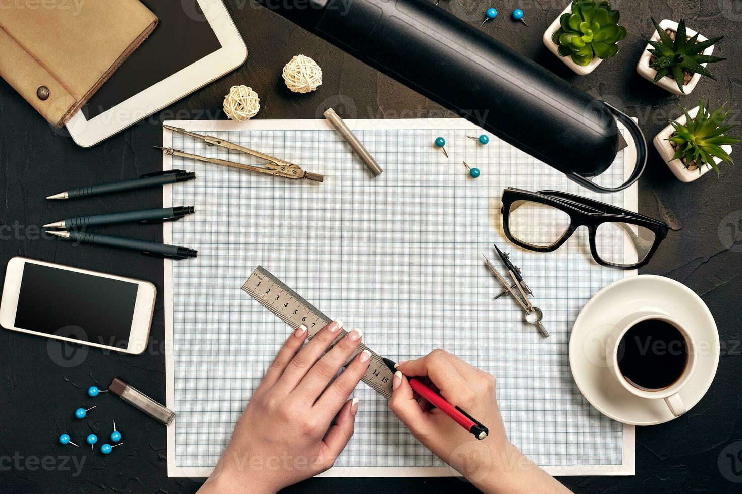 Office desk background hand with pen writing construction project ideas concept. With tablet, drawing equipment and a cup of coffee. View from above photo