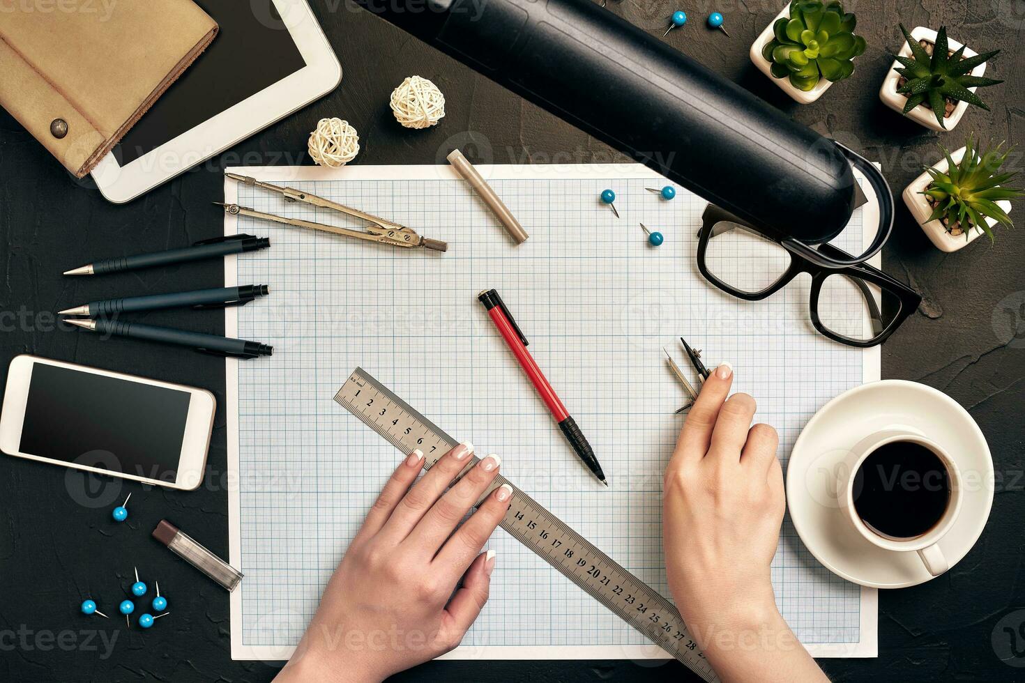 Office desk background hand with pen writing construction project ideas concept. With tablet, drawing equipment and a cup of coffee. View from above photo