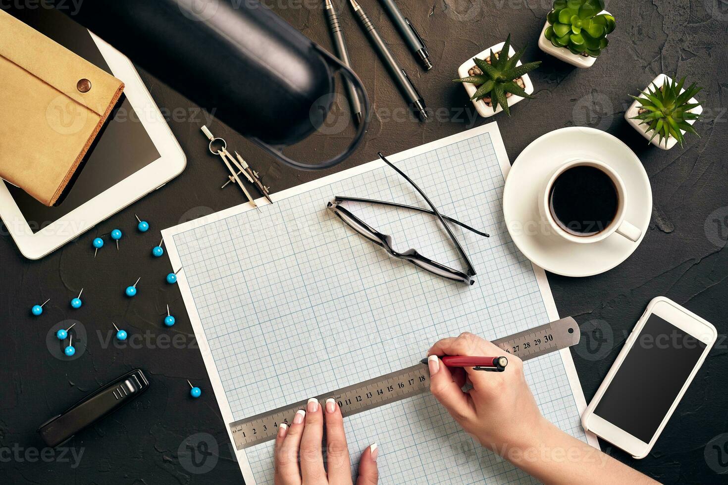 Office desk background hand with pen writing construction project ideas concept. With tablet, drawing equipment and a cup of coffee. View from above photo