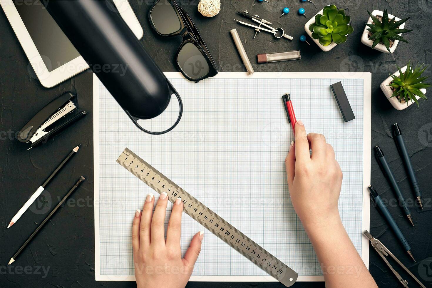 Office desk background hand with pen writing construction project ideas concept, With tablet, drawing equipment and lamp. View from above photo