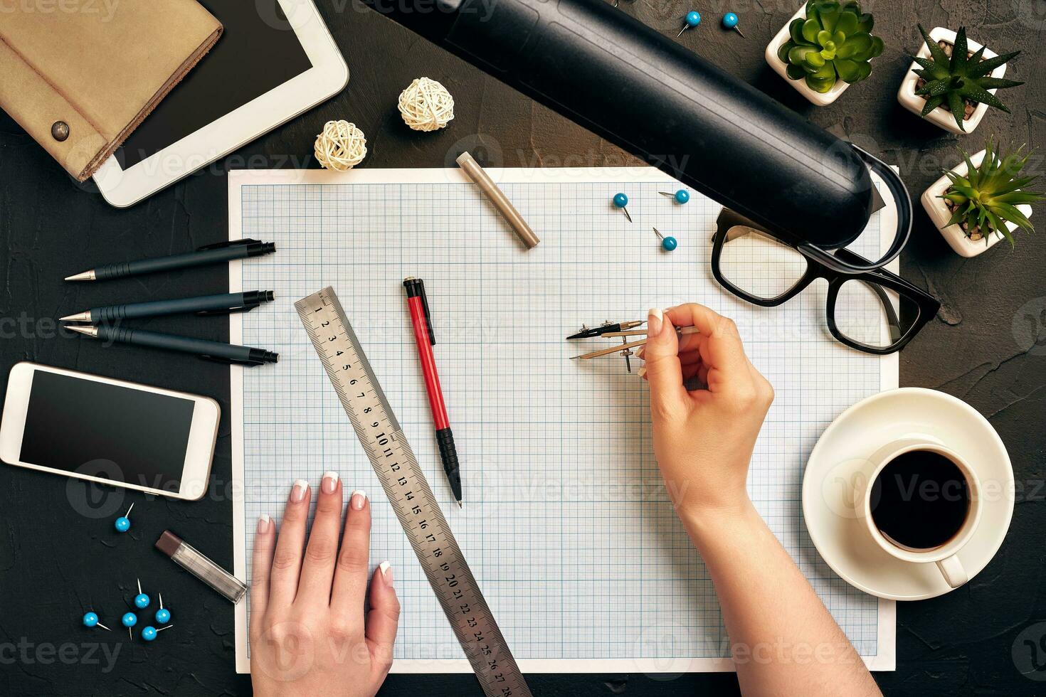 Office desk background hand with pen writing construction project ideas concept. With tablet, drawing equipment and a cup of coffee. View from above photo