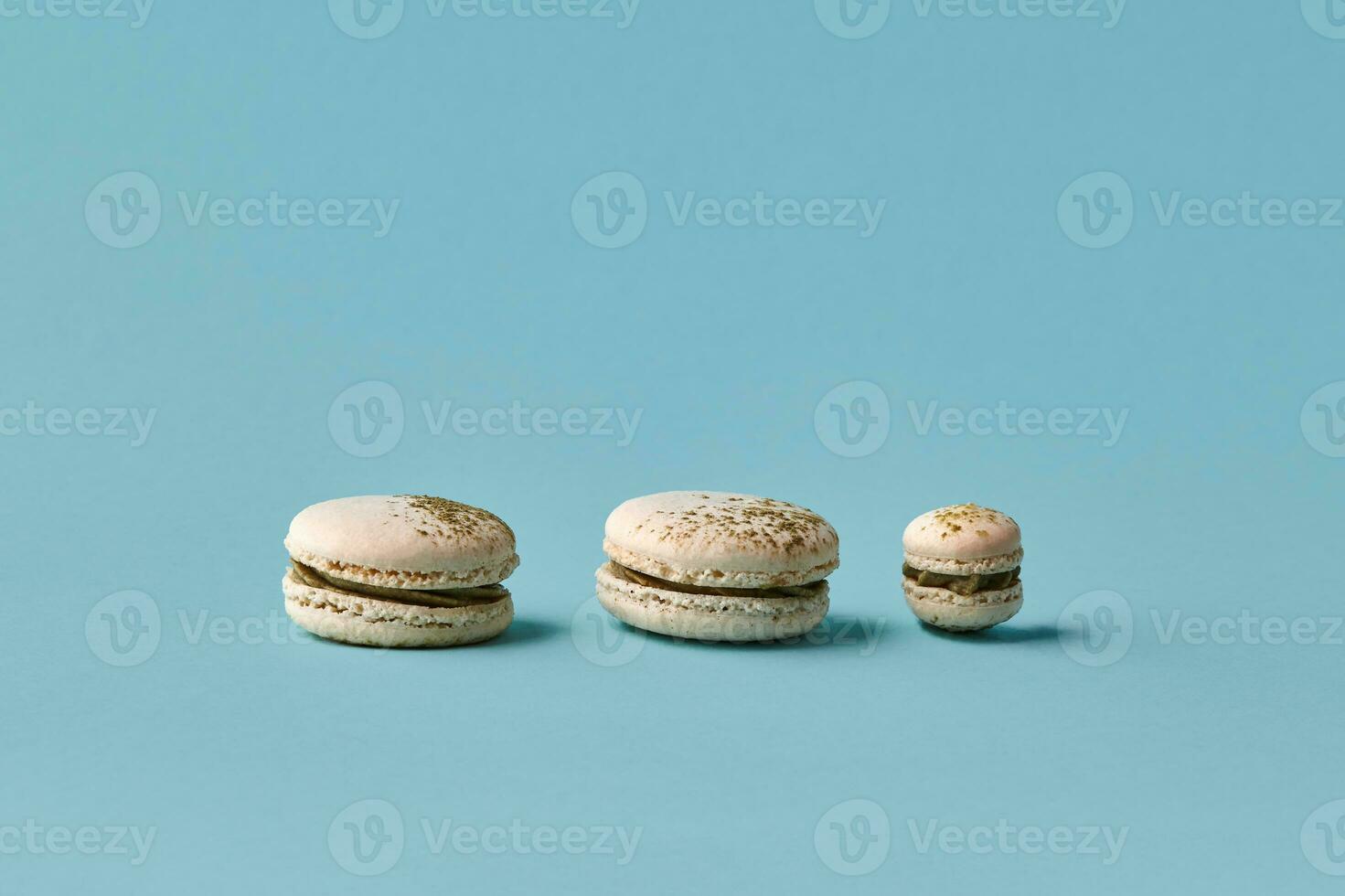 White macarons cake with colorful powder, top view, flat lay, sweet macaroon on blue background. Different size cookies photo