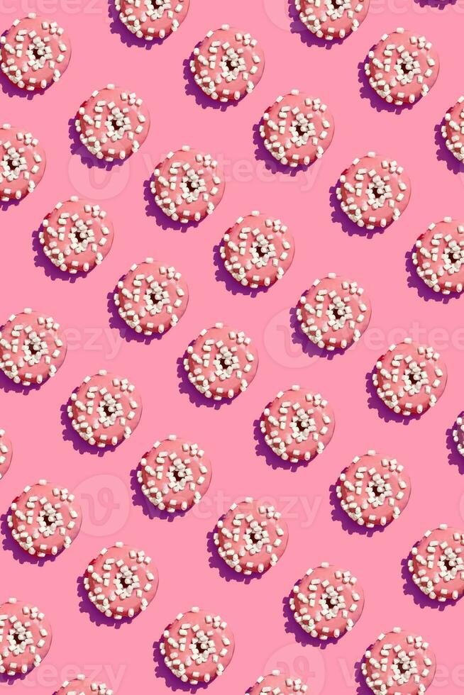 Food design with tasty pink glazed donut on coral pink pastel background top view pattern photo