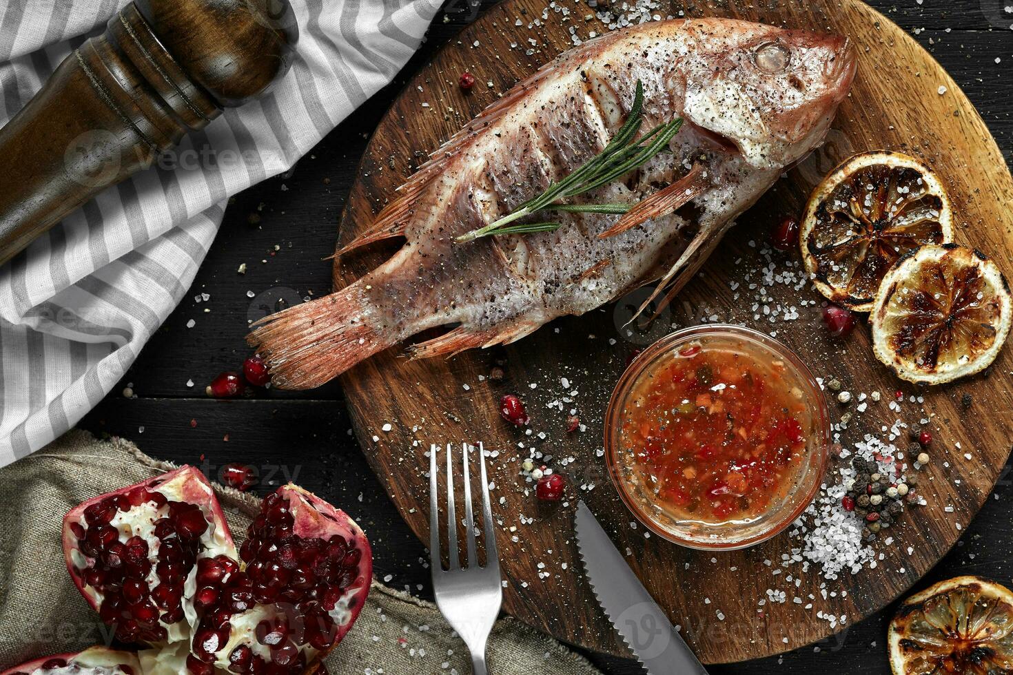 Grilled red mullet on a wooden board with lemon and garnet. Healthy eating concept photo