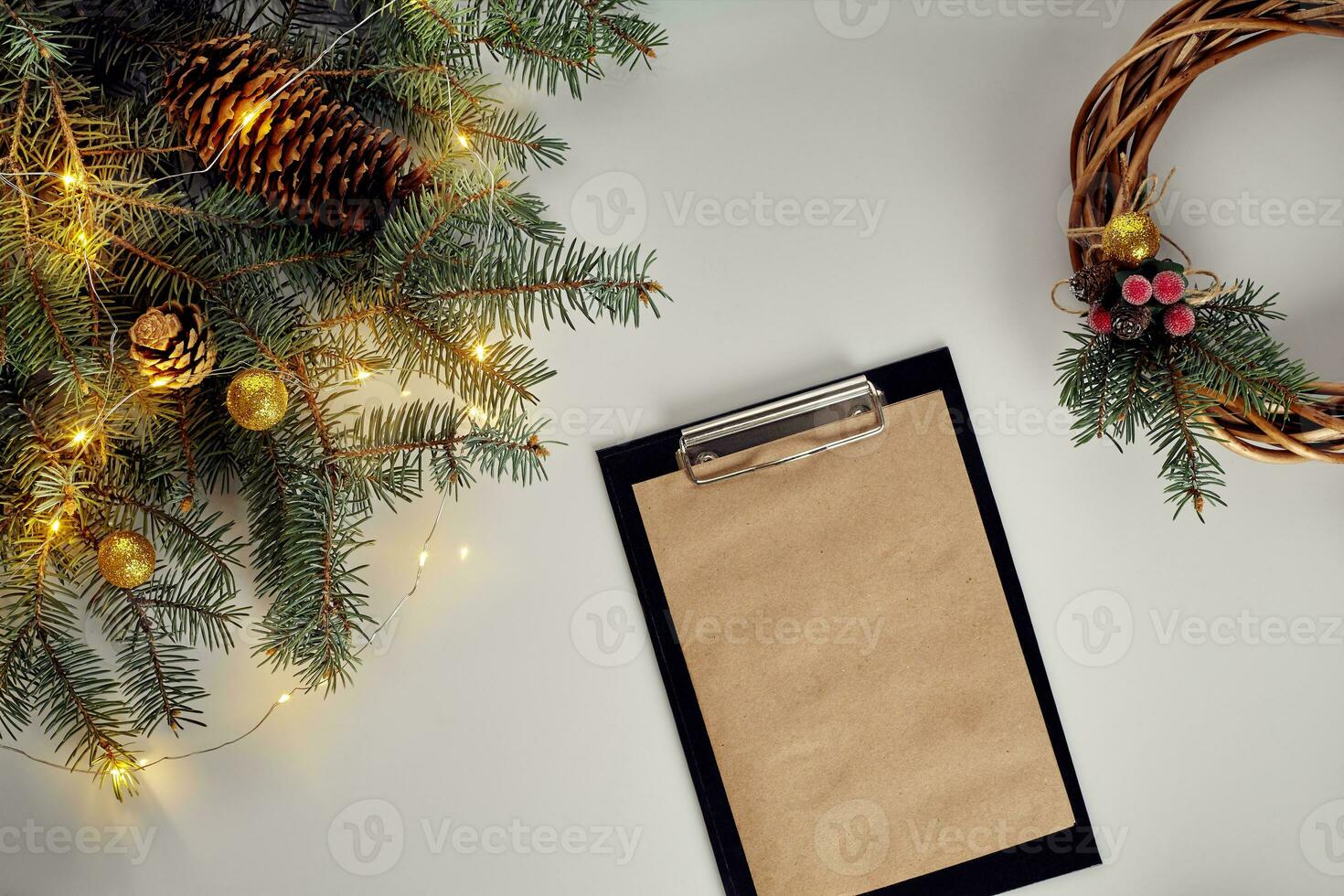 Flat lay of juniper wreath green pine tree branches, wreath and craft paper on white table, top view. photo