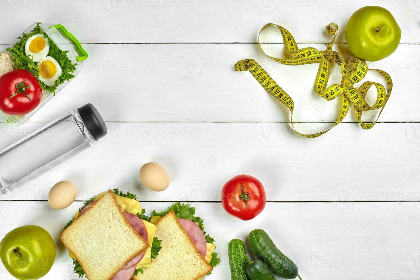 Lunch. Sandwiches and fresh vegetables, bottle of water and green apple on wooden table. Healthy eating concept. Top view photo