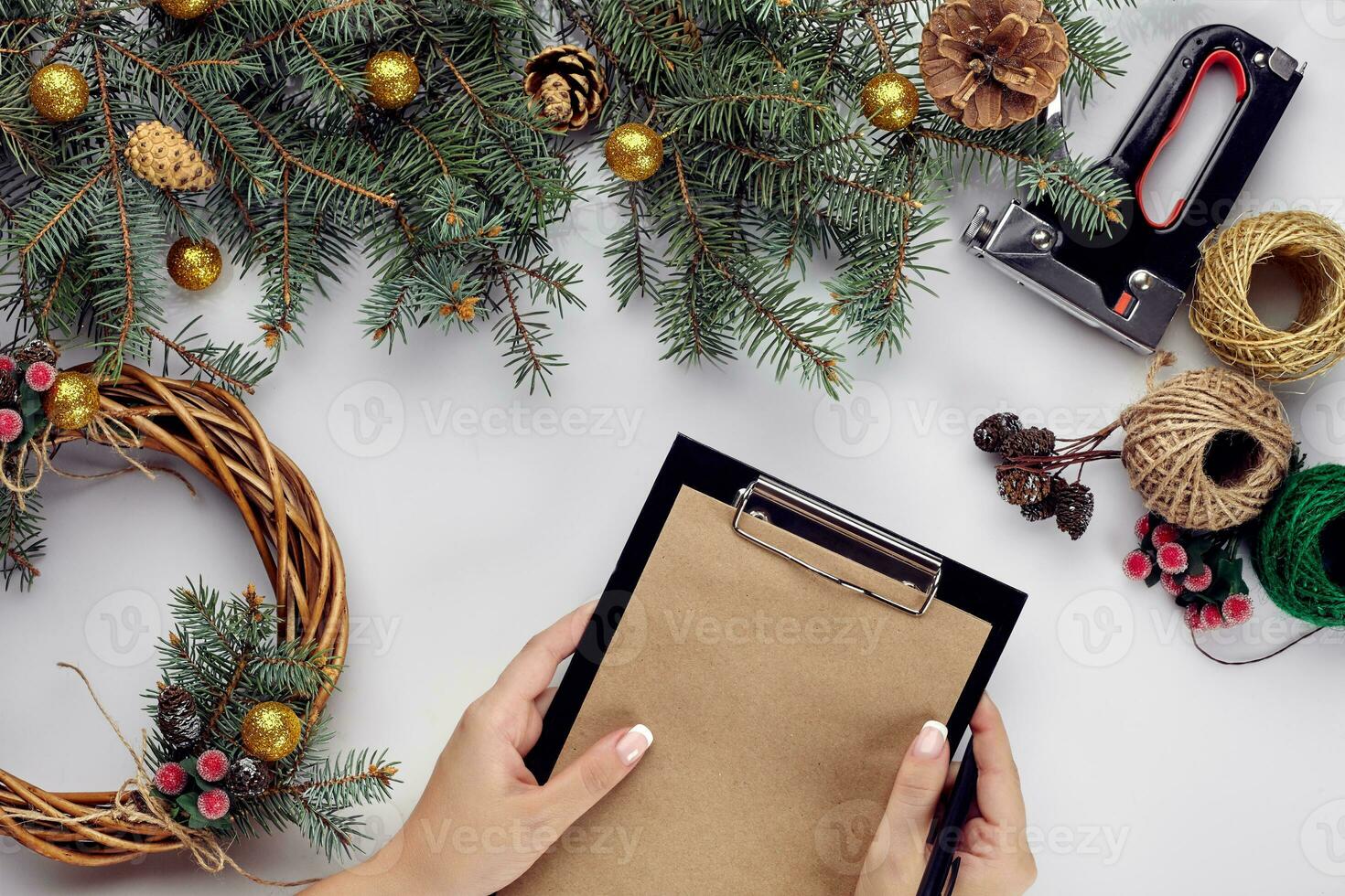 Creative christmas diy. Woman making handmade xmas wreath. Home leisure, tools, trinkets and details for holiday decorations on white table background. Top view photo