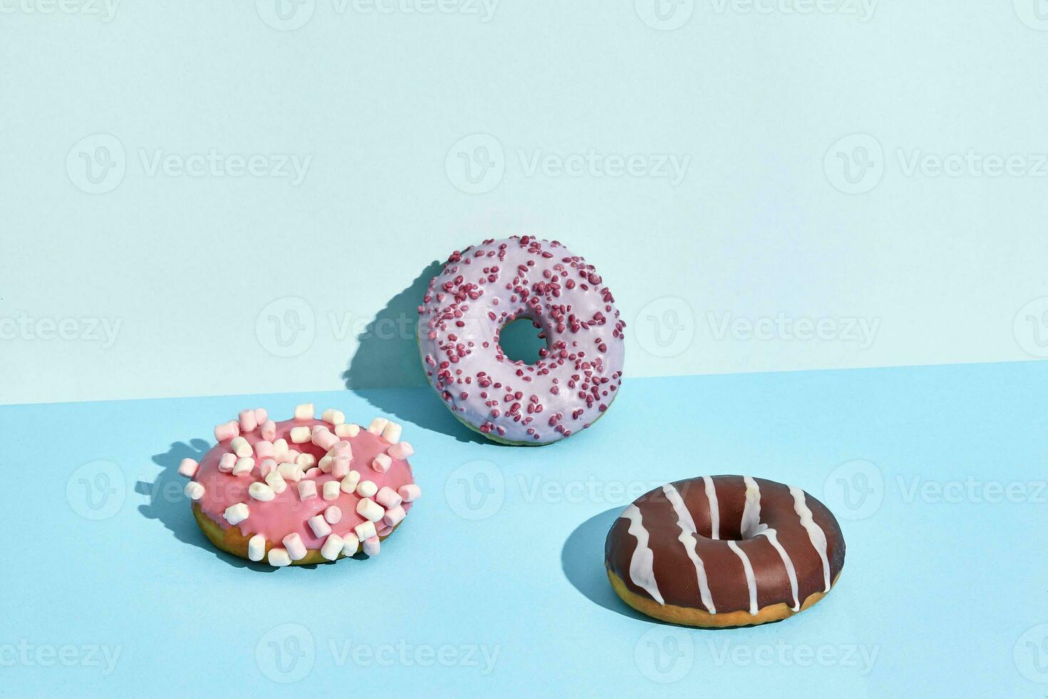 Three sweet tasty donuts in caramel and chocolate icing, on a two-color background photo