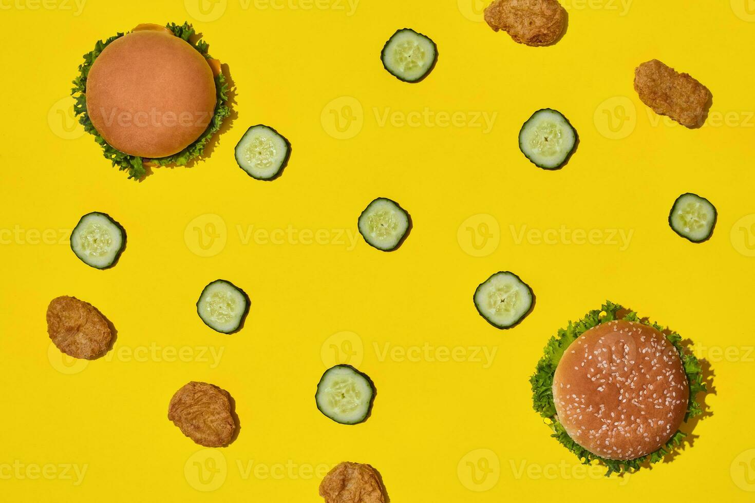 Two tasty fresh unhealthy hamburgers with ketchup and vegetables on yellow vibrant bright background. Top View with Copy Space. photo