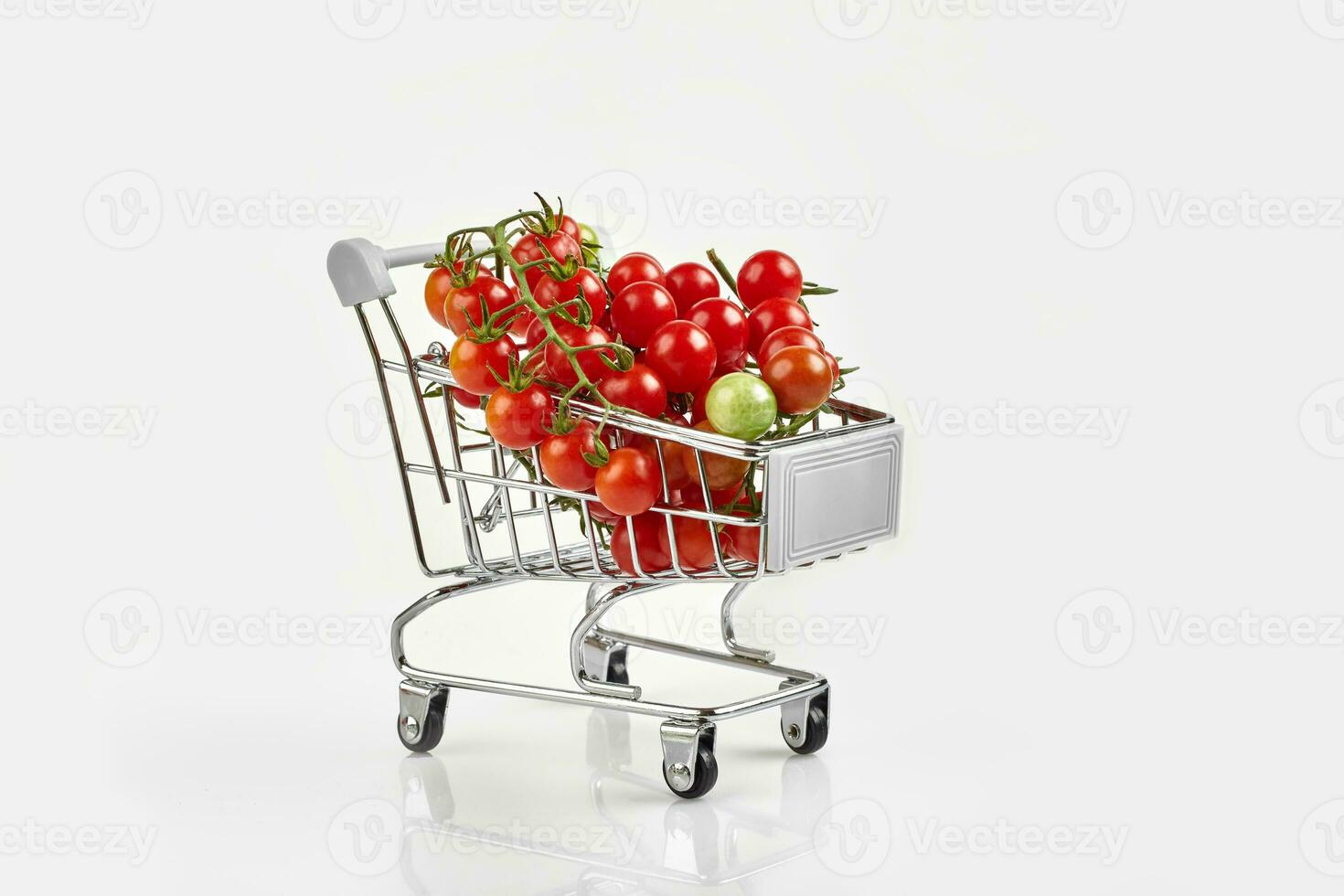 Mini shopping cart full with cherry tomatos on white background photo