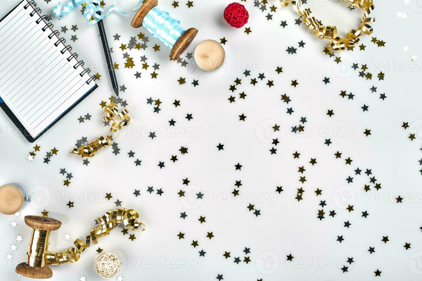 Flat Lay Christmas or Party Background with colored ribbons, decorations, confetti, and wrapping paper. Notepad for Text photo