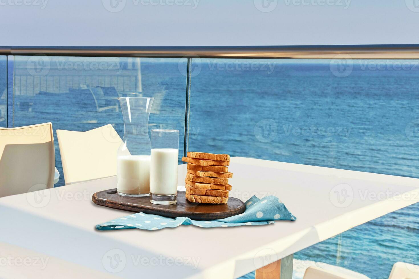 Table for two served with a breakfast on outdoor hotel balcony with a sea view. photo