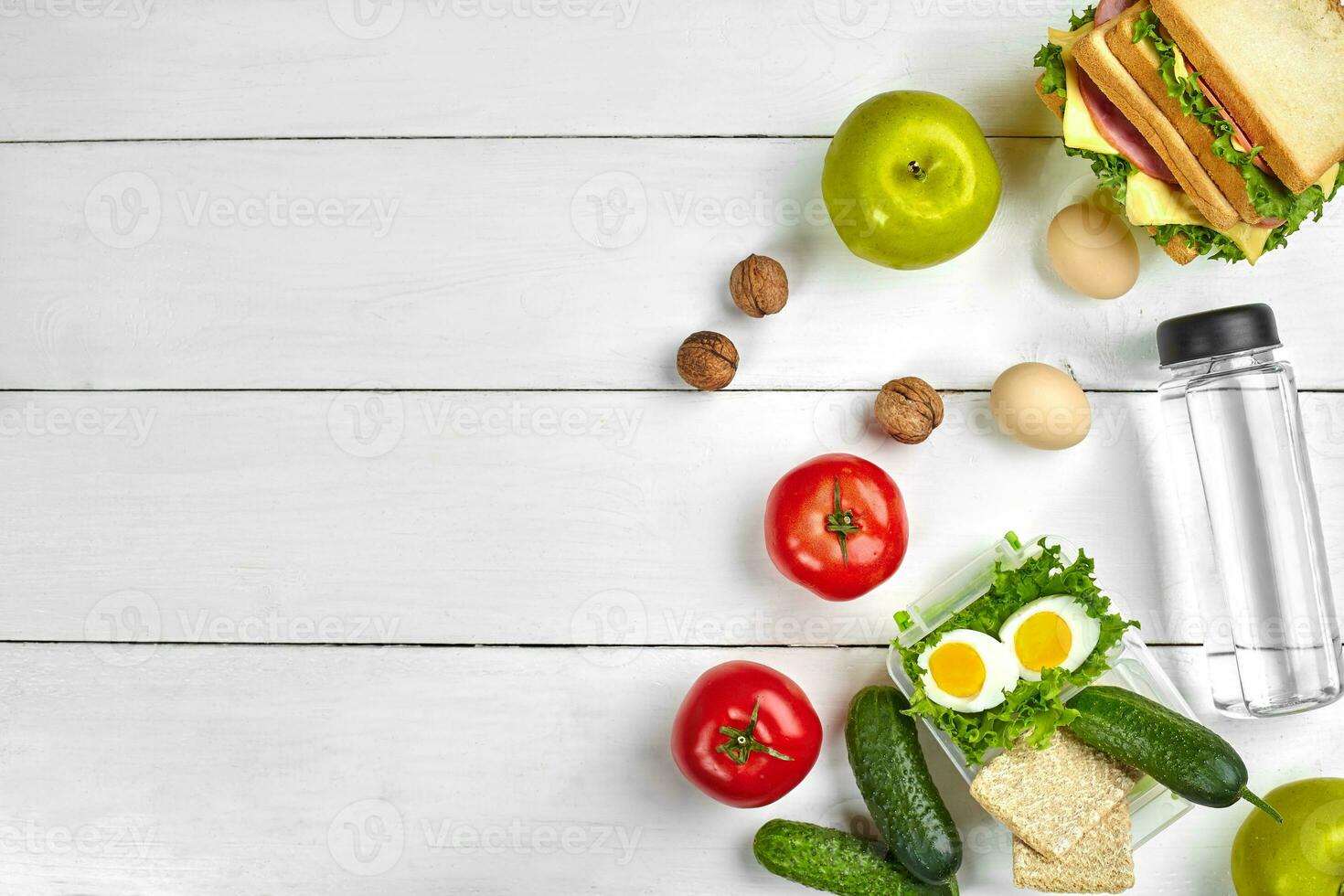 Lunch. Sandwich and fresh vegetables, bottle of water, nuts and fruits on white wooden background. Healthy eating concept. Top view with copy space photo