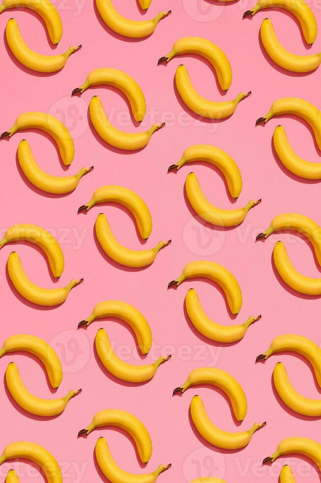 Pattern composition of a pair of bananas lying next to a pink background , top view photo