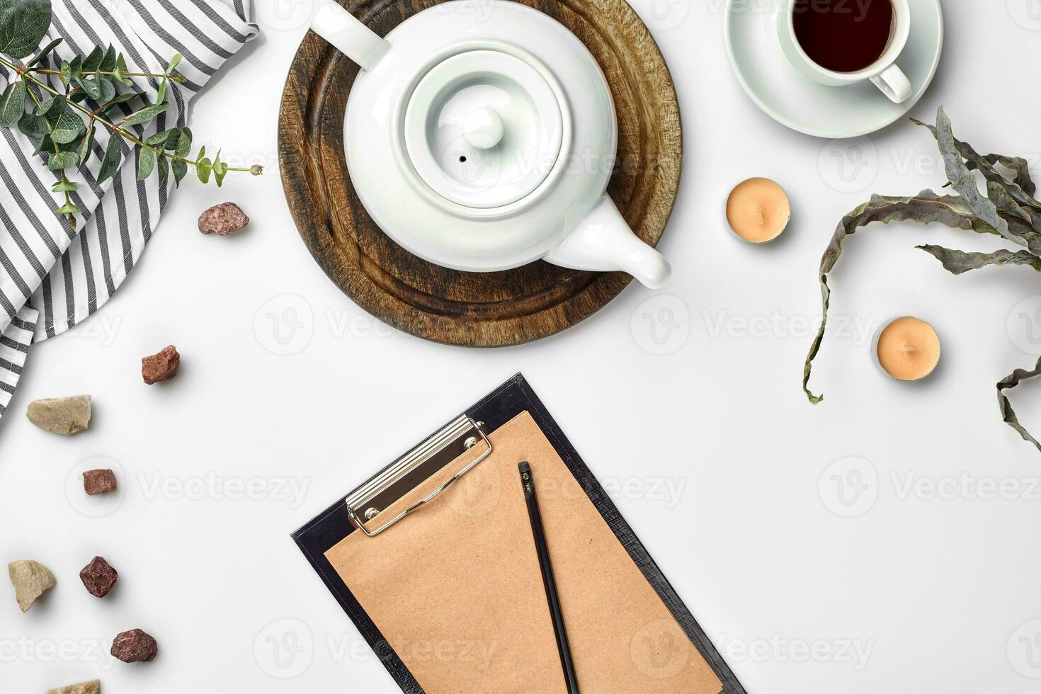 White background on which craft paper, notebook, cup with tea and white porcelain teapot. Romantic breakfast. Top view. Copy space. photo