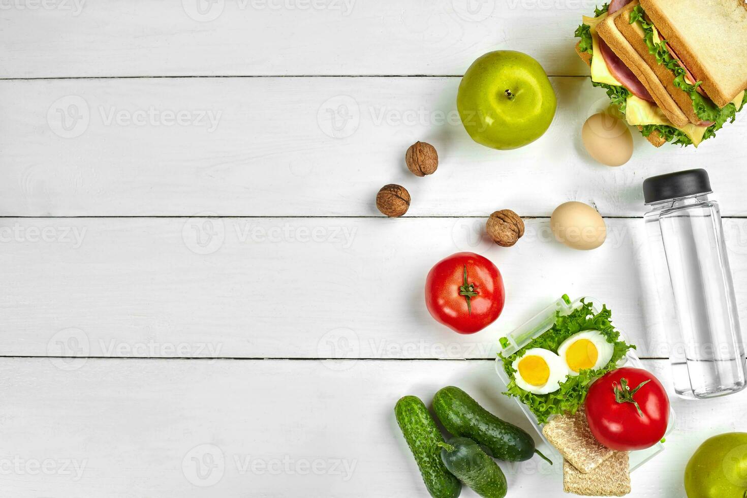 Lunch. Sandwich and fresh vegetables, bottle of water, nuts and fruits on white wooden background. Healthy eating concept. Top view with copy space photo