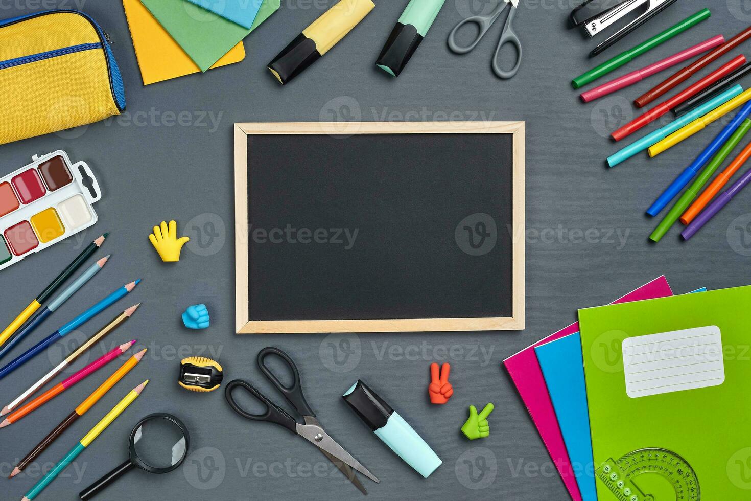 Flat lay photo of workspace desk with school accessories or office supplies on gray background.