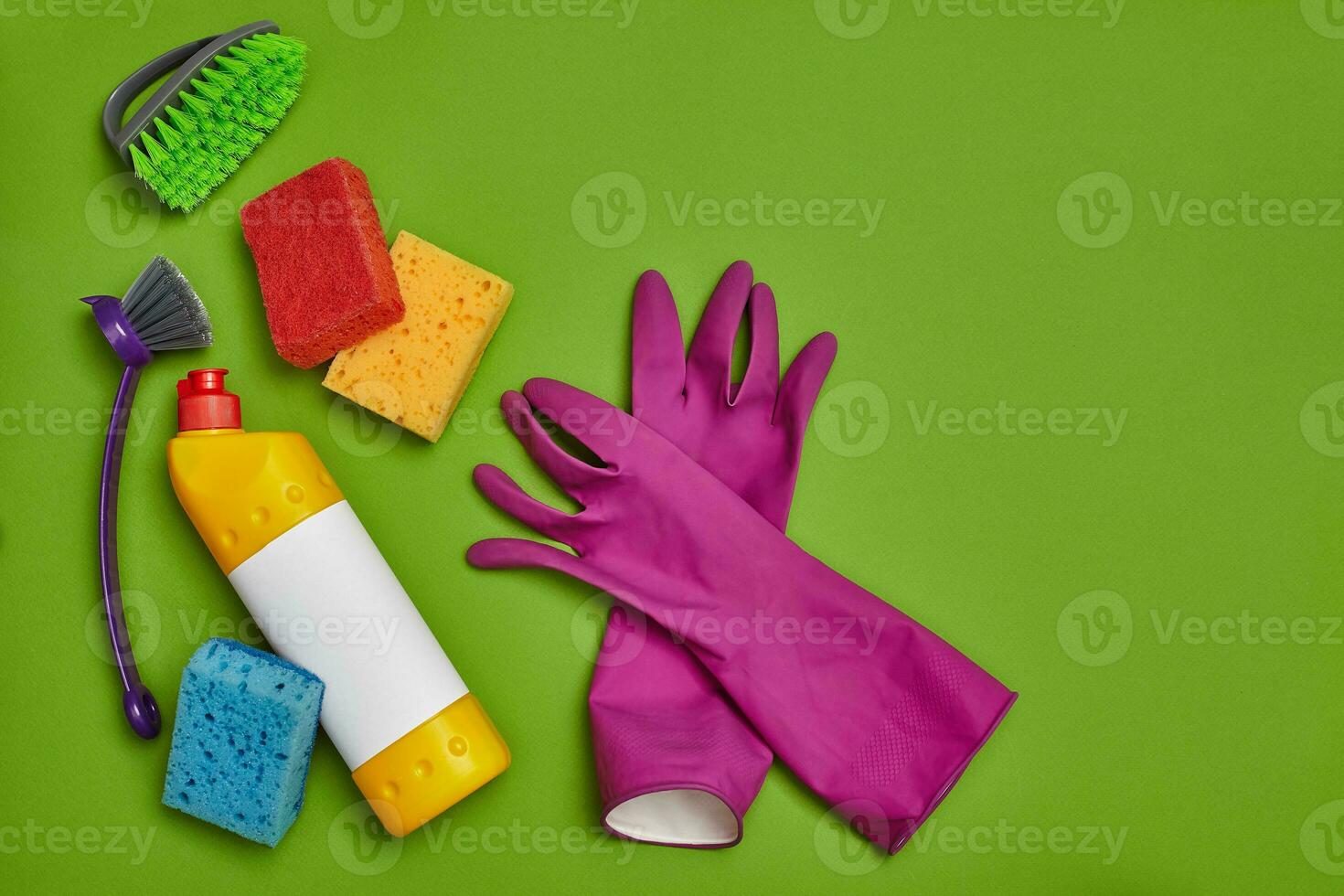 Detergents and cleaning accessories on a green background. Housekeeping concept. photo