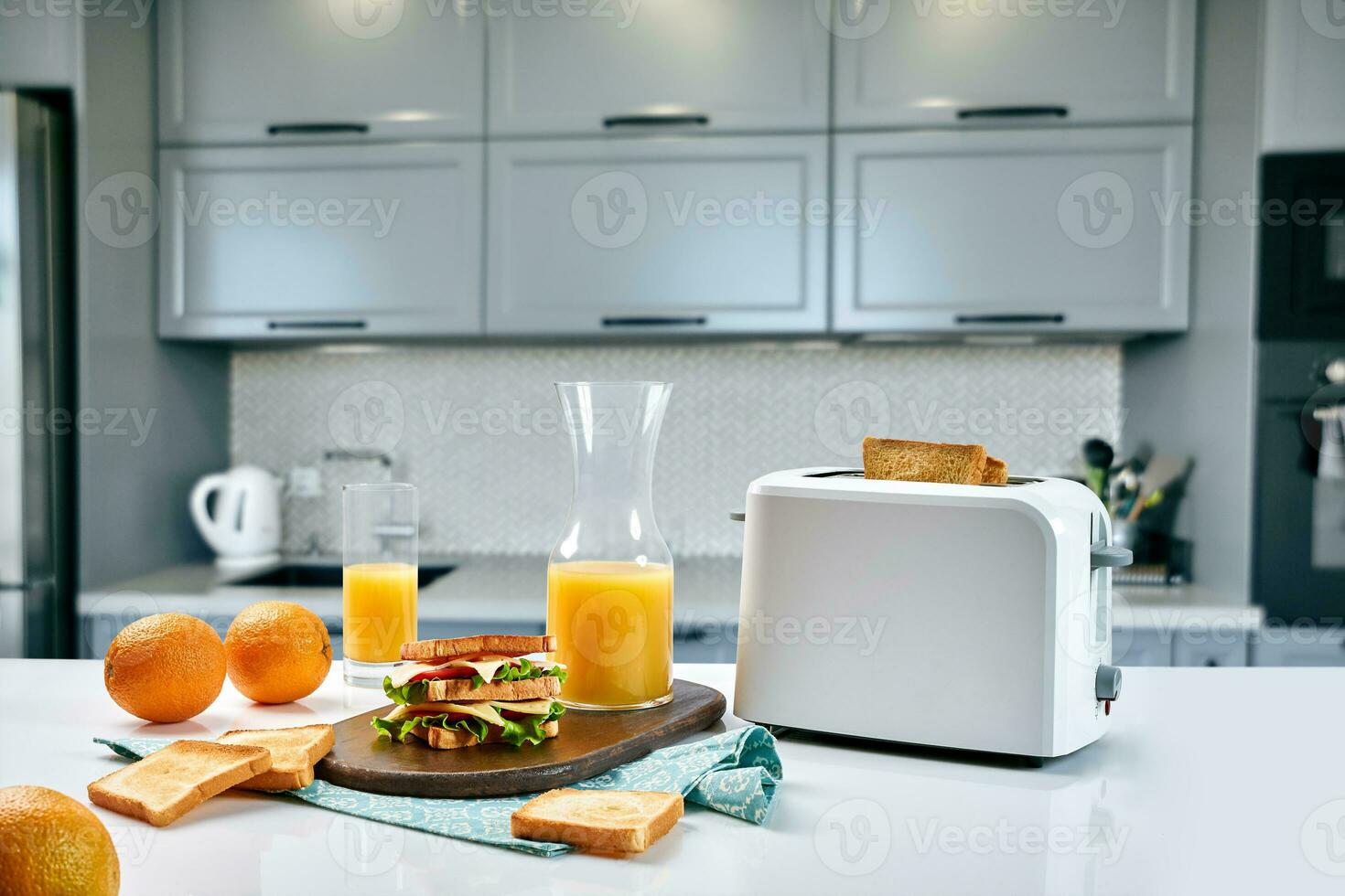 White electric bread toaster with orange juice with sandwich on kitchen table. Breakfast in the cozy kitchen. photo