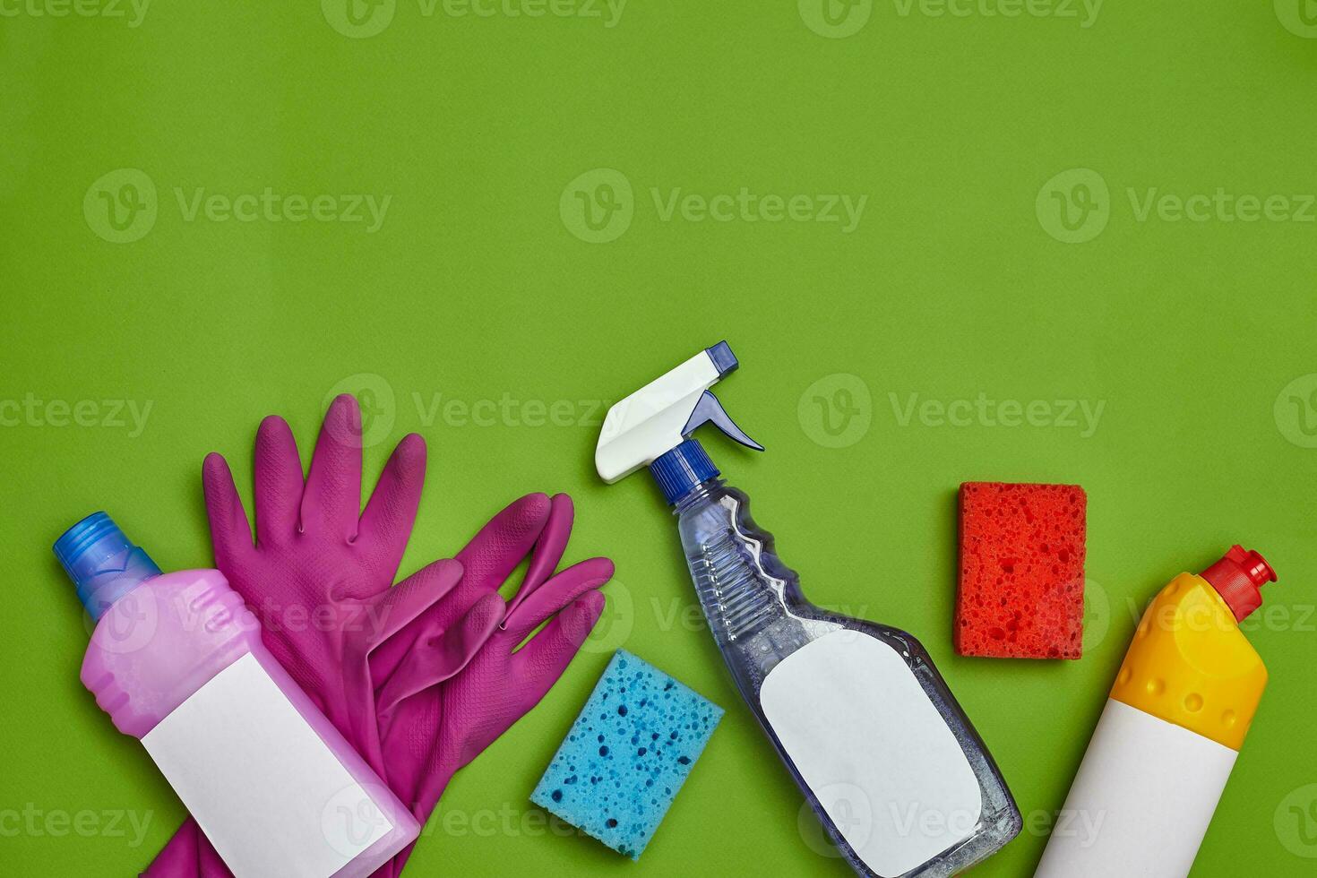 Detergents and cleaning accessories on a green background. Housekeeping concept. photo