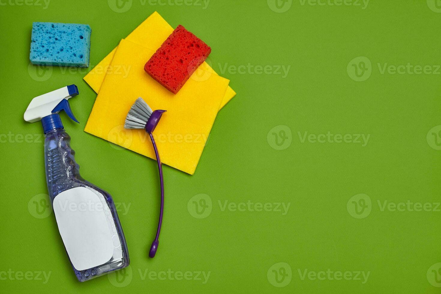 Detergents and cleaning accessories on a green background. Housekeeping concept. photo