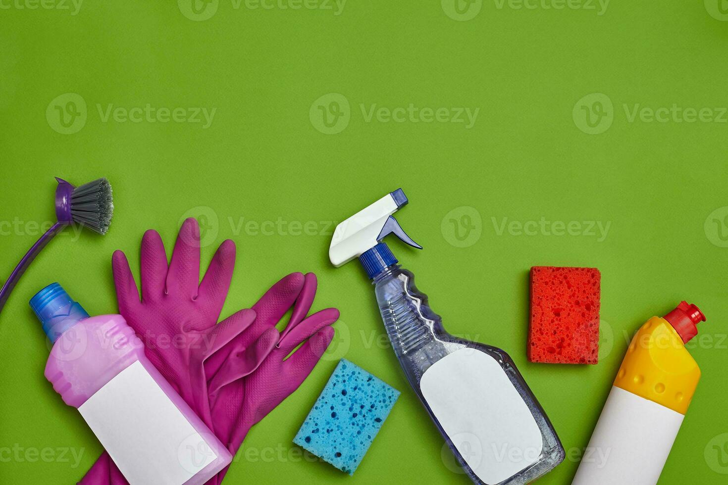 Detergents and cleaning accessories on a green background. Housekeeping concept. photo