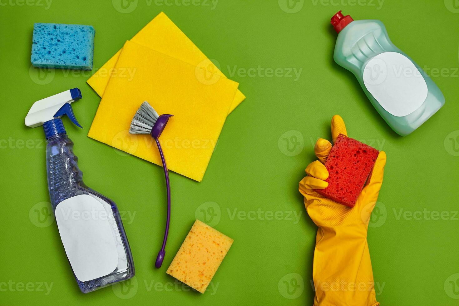 Detergents and cleaning accessories on a green background. Housekeeping concept. photo