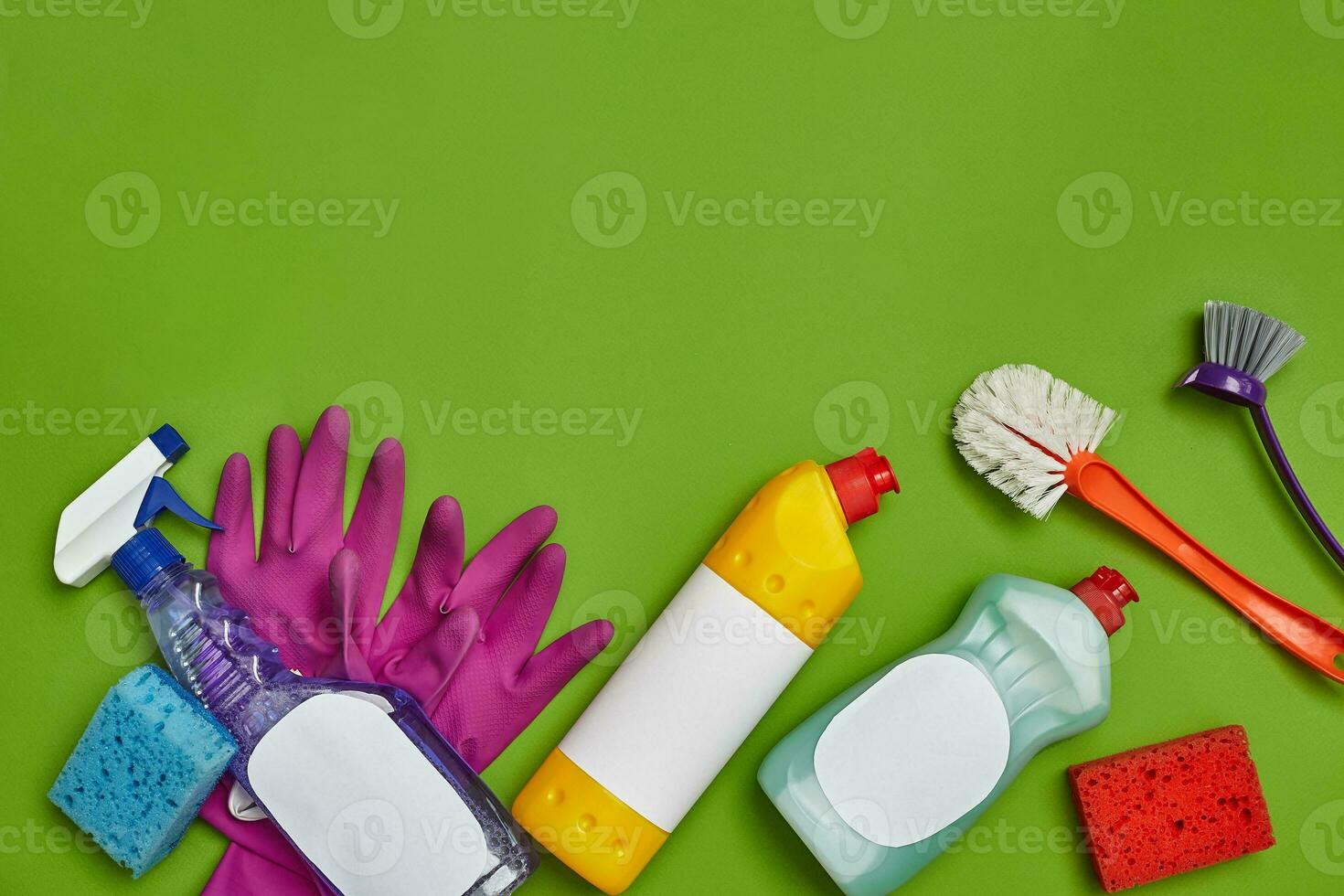 Detergents and cleaning accessories on a green background. Housekeeping concept. photo