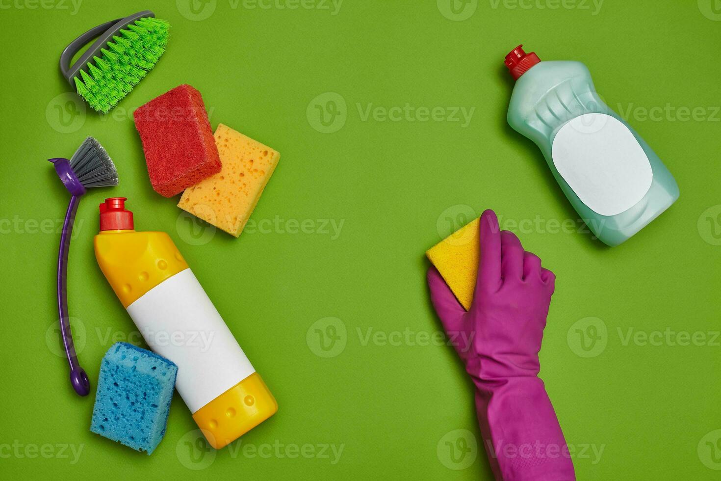 Detergents and cleaning accessories on a green background. Housekeeping concept. photo