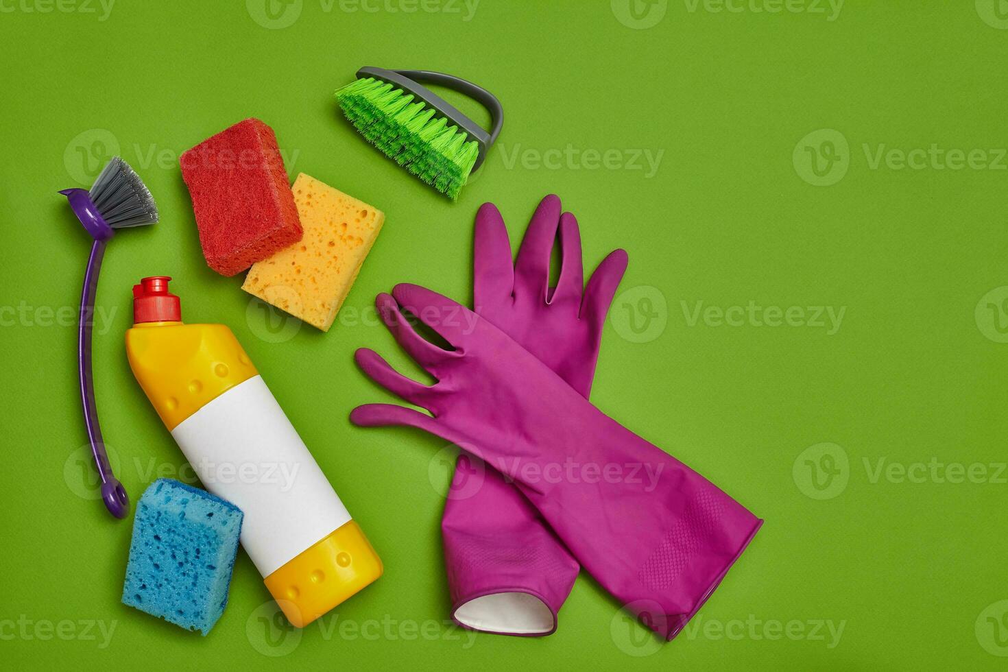 Detergents and cleaning accessories on a green background. Housekeeping concept. photo