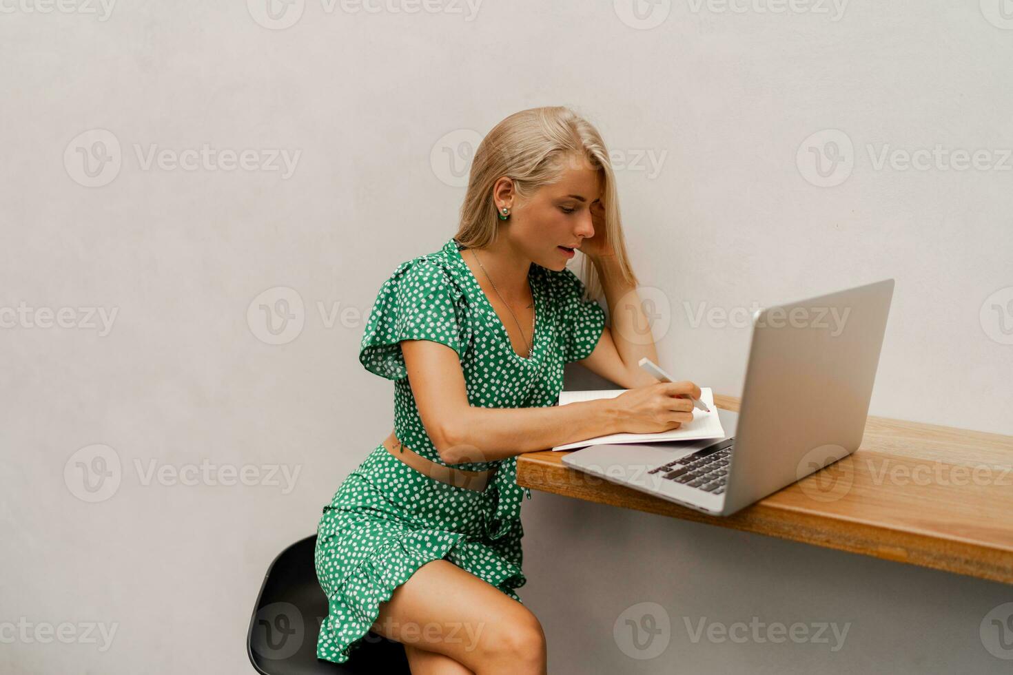 Pretty blond woman using lap top, making notes photo