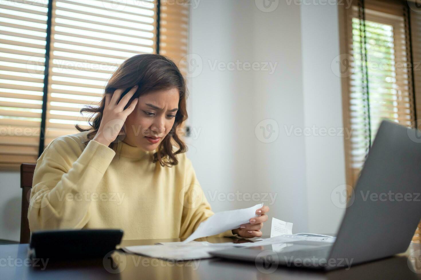 A woman uses a calculator to check the sum of her home expenses and she is stressed over the home expenses. photo