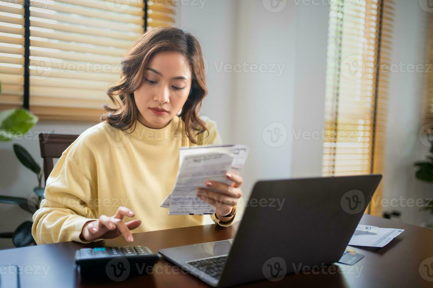 A woman uses a calculator to check the sum of her home expenses and she is stressed over the home expenses. photo