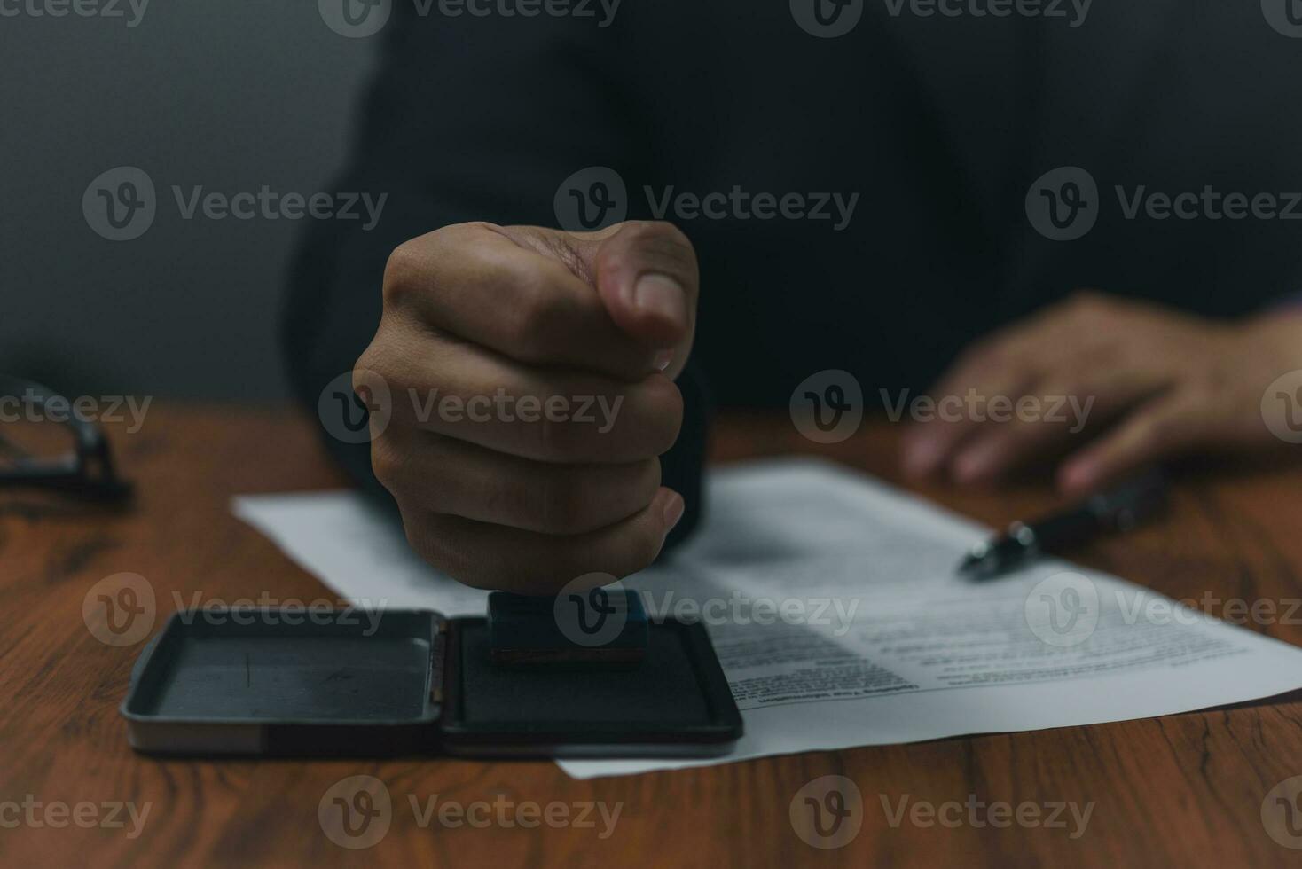 Hand man stamping documents notary public in office . Businessperson stamping approval of work finance banking or investment marketing documents on desk. photo