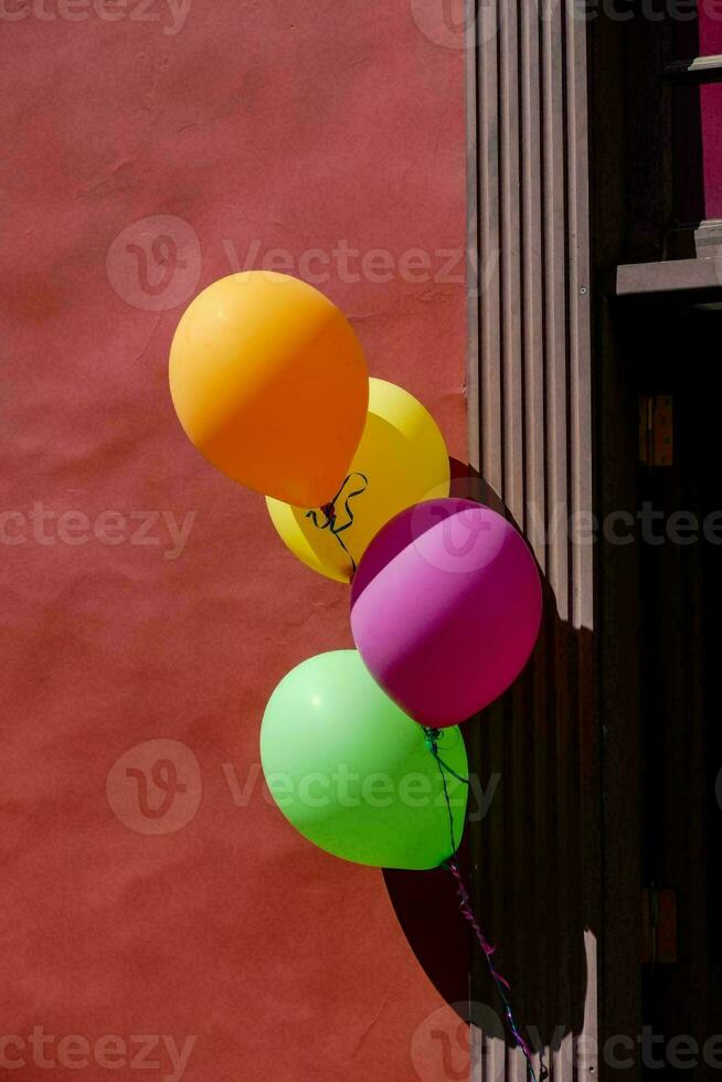 balloons hanging from a wall in front of a red building photo